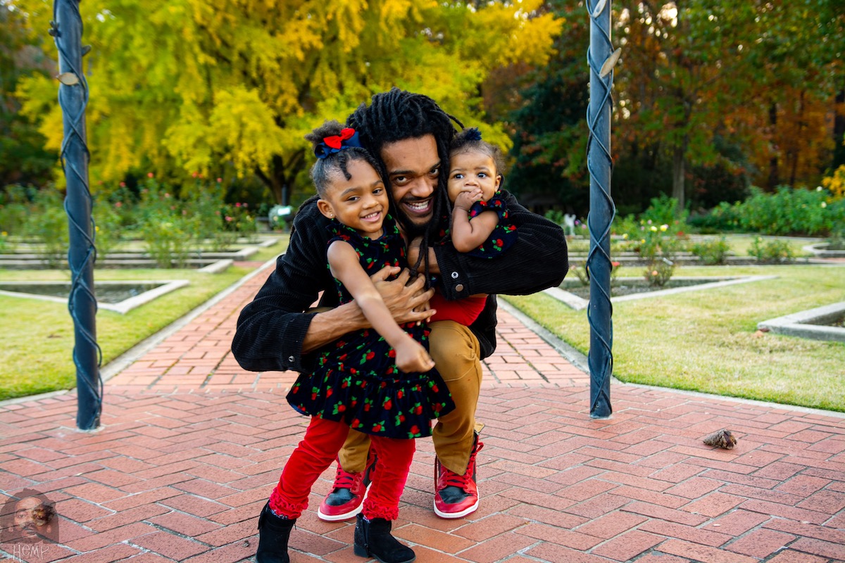 Hemp the Artist embracing his daughters in a garden